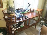 Full view of the pair of two-level wooden end tables showing overall condition with water marks and wear. Tables are placed next to each other with various items on top that are not included.