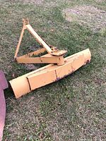 Side view of the yellow steel grader blade attached to triangular frame.