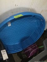 Blue plastic kiddie pool with textured bottom and raised seating, displayed against a wall