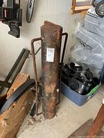 Full view of the heavy duty steel post pounder, stands 37 inches tall, cylindrical with handles, shows rust and wear.
