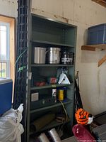 Full view of metal shelving unit with various items placed on shelves for scale and context, showing shelf construction and adjustable shelf holes on side supports.