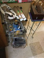 Two metal wire shelves, one dismantled, with various items including cardboard tubes and cords on them.