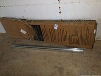 Boxed shower door kit containing metal frame components, approximately 70 inches tall.