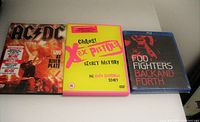 Front view of the three rock music DVDs: AC/DC, Sex Pistols Chaos, Foo Fighters.