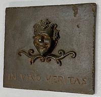 Front angle view showing the full bronzed cast metal plaque with Bacchus relief and inscription.