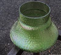 Side angle of Loetz Austria iridescent green vase highlighting dimpled tactile surface texture and shape.