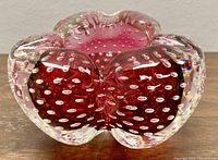 Front angle view of pink Murano bubble glass bowl on wood surface showing detailed bubble pattern, color and gloss.