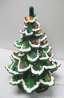 Full view of the ceramic Christmas tree lamp showing green ceramic with white snow trim and colorful translucent bulb lights, missing star on top.