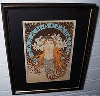 Framed art print of Sarah Bernhardt with hair adorned by white lilies, set in black mat and black frame with gold trim.
