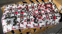 Photo of quilt laid flat showing colorful star patchwork design predominantly in red, white and black colors.