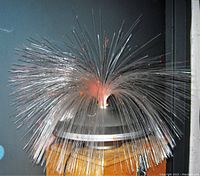 Front view of the space-age flying saucer fiber-optic lamp showing fiber-optic strands lit in red and orange colors.