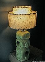 Front and side view of the lamp lit showing ceramic base and shade