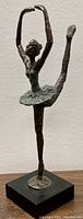 Front left angle of the bronze ballerina statue showing the raised leg and arm pose