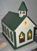 Front and side angled view showing green roof, white walls, and stained glass windows.