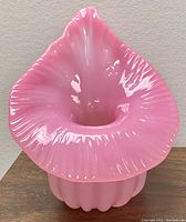 Front view showing the ruffled, flared vase opening and pleated base in opalescent pink glass.