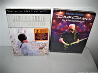 Front view of two unopened DVD cases featuring Jimi Hendrix Live at Woodstock and David Gilmour Remember That Night Live at Royal Albert Hall.