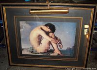 Frontal view of large male nude art print in ornate frame with working twin-bulb picture light above.