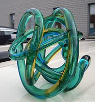 Front angled view of the tri-coloured twisted knot sculpture showing its glass loops and color transitions.