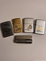 Top view of 5 lighters: 4 Zippos with different engravings and 1 IMCO Triplex lighter