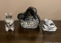 Front view of three animal resin carvings: raccoon, goose, and seal.