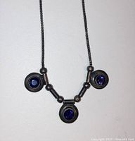 Close-up image of necklace centerpiece showing three round amethyst stones set in circular sterling silver bezels