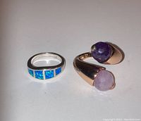 Photo showing two sterling silver rings: one with blue inlay stones and one with two raw purple/lavender gemstones on an open band.