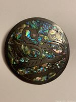 Top view of round sterling silver pendant with abalone inlay showing two swans and colorful shell background