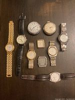 Top-down view of all 10 vintage watches displayed on dark surface showing variety of designs and bands