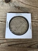 1966 Canadian silver dollar coin front (reverse) side with canoe design and year 1966 in protective cardboard cover.