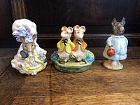 Three Beswick Beatrix Potter porcelain figurines on wooden surface: piglet, two mice, squirrel