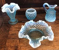 Four vintage blue hobnail glass items placed together on a wood surface showing the set.