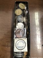 Full view of the long cardboard box filled with coins and tokens