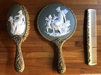 Hand mirror, brush, and comb laid flat on wooden surface, showing front cameo jasper designs and gold-tone ornate handles.