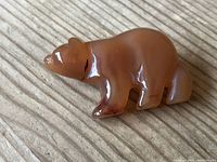 Top view showing polished reddish-brown carnelian bear-shaped brooch with natural color variations.