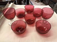 Top view of all 8 glassware pieces arranged on white paper, showing 2 stemmed glasses and 6 stemless glasses