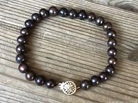 Full view of chocolate-colored South Sea pearl bracelet on wooden surface, showing the general appearance and pearl arrangement.