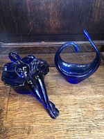 Photo showing the cobalt blue reclining woman bowl and swan-shaped bowl side by side on wooden surface.