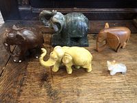 Group of five elephant carvings of different sizes and materials arranged on a wooden surface.