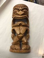 Full view of carved tiki figure lying on flat surface