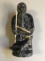 Front view of Inuit sculpture showing hunter in parka holding spear and seal.