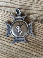 Front side of the Scottish silver pendant displaying the Highlander figure distinctly in raised detail on a cross-shaped backing.