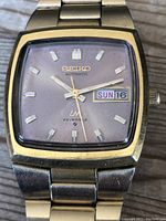 Front close-up of watch face showing Seiko LM Automatic labeling, 23 Jewels, day and date display, and condition details.