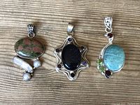 Top-down view of three gemstone pendants on wood surface showing all pendants and details