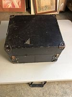 Closed black portable case with metal corner protectors and handle.