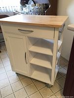 Freestanding butcher block cart showing wooden top, drawer, cabinet door and open shelves on wheels.