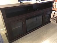 Front view of dark brown sideboard credenza with open shelves, glass-door cabinets and central electric fireplace