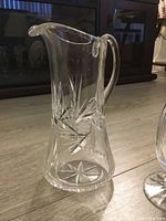 Clear image of Waterford crystal pinwheel pattern pitcher with handle and spout on floor