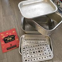 Overall view of the vintage large roaster, inner perforated racks stacked and a vintage recipe booklet.