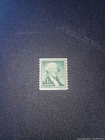 Photo of one 1-cent green George Washington U.S. postage stamp on a dark background showing the front face with clear portrait and denomination.