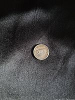 Obverse side of the 1967 Canadian silver centennial quarter showing the bobcat design, placed on a black fabric background.